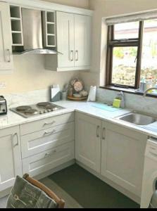 een keuken met witte kasten, een wastafel en een raam bij Townhouse Wexford in Wexford