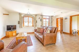 a living room with a leather couch and a tv at Swallow's Nest in Craven Arms