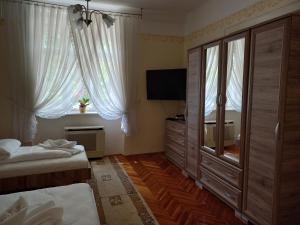a bedroom with two beds and a flat screen tv at Szent István Wellness Panzió in Makó