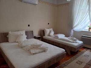 two beds sitting in a room with a window at Szent István Wellness Panzió in Makó