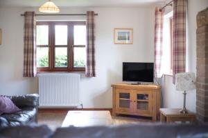 a living room with a tv on a wooden stand at Byne Brook Cottage in Wistanstow