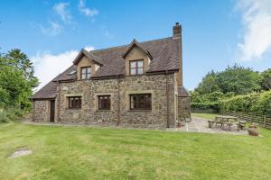 an old stone house with a picnic table in the yard at Byne Brook Cottage in Wistanstow