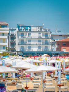 a beach with chairs and umbrellas and a large building at Hotel Riviera in Caorle