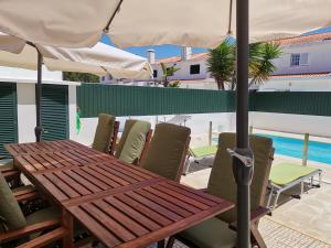 una mesa de madera y sillas bajo una sombrilla en el patio en Casa Praia e Ria en Torreira
