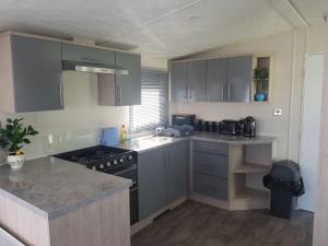 a kitchen with gray cabinets and a stove top oven at St Osyth New Holiday Home in Jaywick Sands