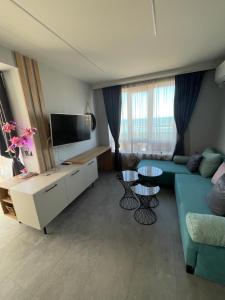 a living room with a blue couch and a tv at Апартаменти Генезис Ахтопол in Ahtopol