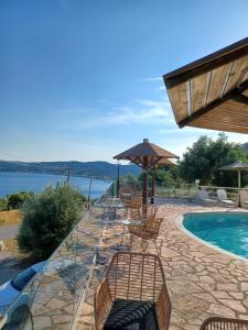 a patio with chairs and a pool with a view of the water at Stefanosplace ApartHotel Sea View in Barbati