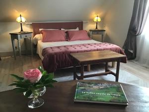 Un dormitorio con una cama y una mesa con un libro en La Meunière, en Jouy