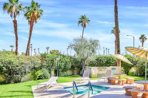 a pool with chairs and tables and palm trees at Esprit Vacation Condo in Palm Springs