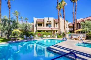 a swimming pool with palm trees and a building at Esprit Vacation Condo in Palm Springs