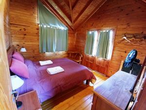 1 dormitorio con 1 cama en una cabaña de madera en Cabañas El Refugio de Puelo en Lago Puelo