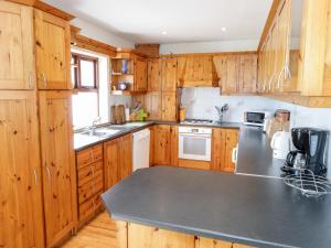 a kitchen with wooden cabinets and a gray counter top at King Cottage in Cleggan
