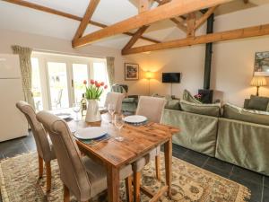 uma sala de jantar e sala de estar com uma mesa de madeira e cadeiras em Shepherds Burn Cottage em Greenhaugh