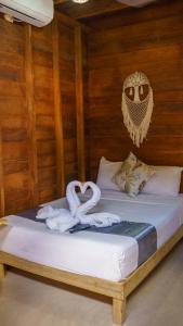 1 cama con toallas y una decoración de búho. en Cabañas Chac Mool en Holbox Island