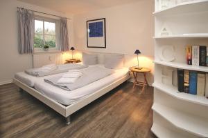 a bedroom with a large white bed and bookshelves at Badestra_e 18 a_ Whg_ 1 in Wyk auf Föhr