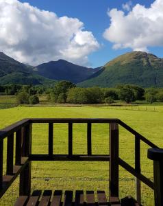a fence with a view of a field and mountains at Oakview Chalet in Glencoe