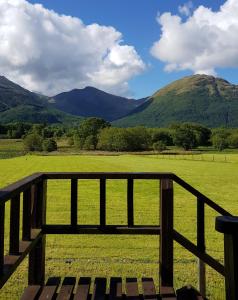 una valla con vistas a un campo y a las montañas en Oakview Chalet, en Glencoe