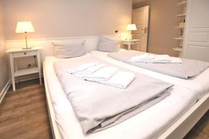 1 cama blanca grande con 2 toallas blancas. en Badestra_e 18 a_ Whg_ 4, en Wyk auf Föhr