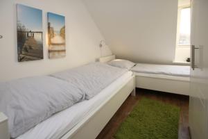 - une chambre blanche avec 2 lits et une fenêtre dans l'établissement Badestra_e 80_ Whg_ 8_ Goting Hus, à Wyk auf Föhr