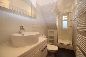 ein weißes Bad mit einem Waschbecken und einem WC in der Unterkunft Am Grünstreifen 31, Whg. 6 "Strandgut" in Wyk auf Föhr