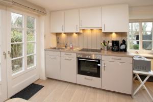 a kitchen with white cabinets and a stove top oven at But Doerp 3_ Whg_ 3 in Wyk auf Föhr