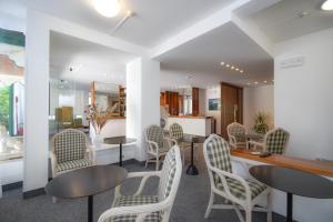 una sala de espera con sillas, mesas y un espejo en Hotel Janeiro, en Caorle