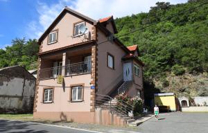 une femme qui passe devant une maison rose dans une rue dans l'établissement Rooms Odmaralište Jablan, à Senj