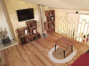 a living room with a tv and a wooden floor at AU NID DES VIGNES in Cahuzac-sur-Vère