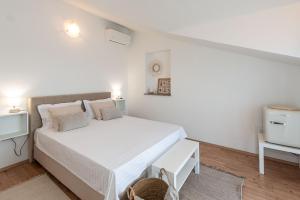 a white bedroom with a large bed and a tv at Guest house DaLi in Rovinj