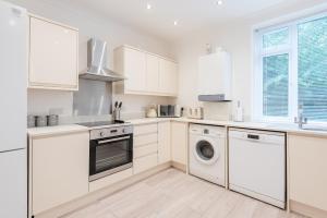cocina con armarios blancos, lavadora y secadora en Hilltown Apartment en Dundee