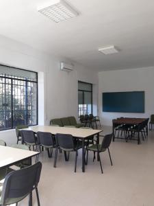 une salle de classe vide avec des tables, des chaises et un écran dans l'établissement Albergue Alagón Natura, à Valdeobispo