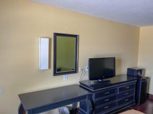 a room with a desk with a television and a mirror at Deluxe Inn & Suites in Corpus Christi