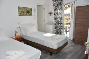 una camera d'albergo con due letti e una finestra di Metapontis Studios (Nimporio) a Sými