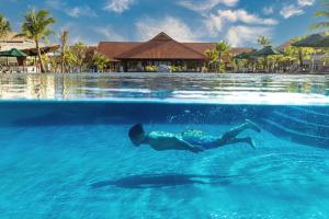 Ein Mann, der im Wasser im Pool schwimmt. in der Unterkunft TUI BLUE Nam Hoi An Resort in Tam Kỳ