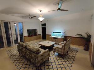 a living room with a couch and chairs and a tv at Vedica Vatica in Shivpuri