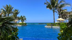 une piscine avec des palmiers et l'océan en arrière-plan dans l'établissement Long Hải Villas trong Wyndham garden Cam Ranh, à Cam Ranh