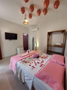 a bedroom with a bed with red flowers and balloons at Recanto Caiçara Pousada in São Miguel dos Milagres