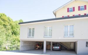 une maison blanche avec un garage avec une voiture. dans l'établissement Zwei Zimmer Ferienwohnung Rabiusa Churwalden, à Churwalden