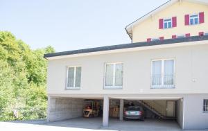 a white house with a garage with a car in it at Zwei Zimmer Ferienwohnung Rabiusa Churwalden in Churwalden