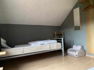 Gîte le Masbourgeois في Nassogne: غرفة نوم مع سرير ومقعد في غرفة
