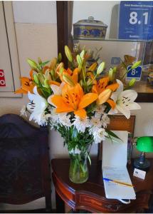 eine Vase voller orangefarbener und weißer Blumen auf dem Tisch in der Unterkunft Hotel Residencial Alentejana in Coimbra