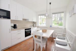 a kitchen with white cabinets and a table and chairs at Wiesenweg 4a, Whg 3 in Wyk auf Föhr