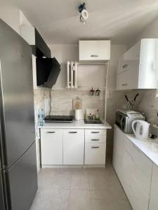 a small kitchen with white cabinets and a refrigerator at Apartament 9 PIĘTRO in Toruń