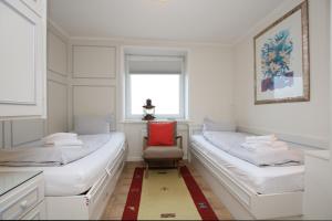 ein weißes Zimmer mit 2 Betten und einem roten Stuhl in der Unterkunft Königstr.5, Whg. 33, Atlantischer Hof in Wyk auf Föhr