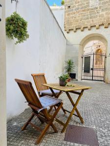 une table en bois et deux chaises installées à côté d'un bâtiment dans l'établissement CASETTA CARENS nel centro storico di Nardò, à Nardò