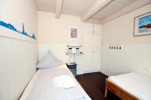 2 Betten in einem kleinen Zimmer mit weißen Wänden in der Unterkunft Susanne-Fischer Weg 37, Haus Einsiedlerkrebs in Wyk auf Föhr