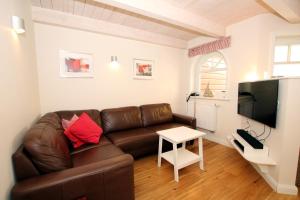 a living room with a brown leather couch and a table at Susanne-Fischer Weg 39, Haus Knurrhahn in Wyk auf Föhr