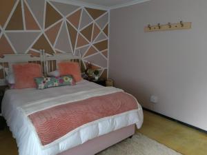 a bedroom with a large bed with pink pillows at VESA Guesthouse in Meyerton