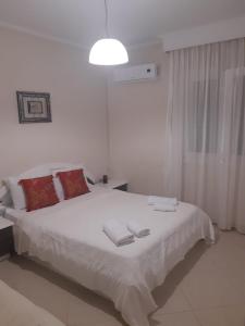 Un dormitorio blanco con una cama grande con toallas. en Holly George Villa, en Nea Plagia