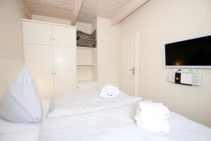 Habitación blanca con muebles blancos y TV de pantalla plana. en Susanne-Fischer Weg 55, Haus Steinbutt, en Wyk auf Föhr